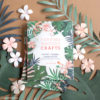 Cutting machine crafts books on a flat lay with tropical flowers
