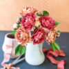 Frosted paper pink and orange camellia flower arrangement in vase