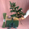 Crepe paper christmas tree held by hand with pink ornaments on it
