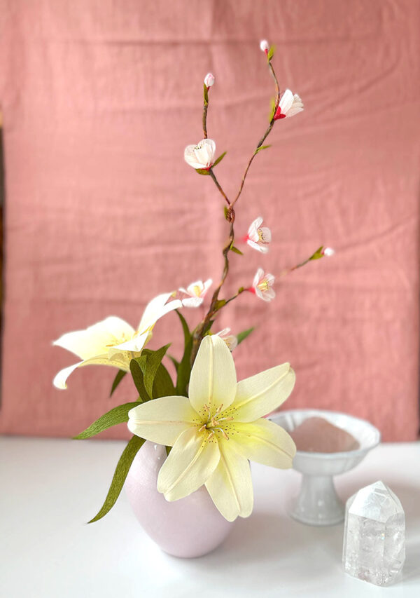 yellow crepe paper lily and quince branch arrangement in pink vase