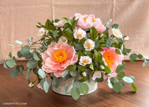 crepe paper arrangement in white and gold vase on table