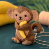 DIY Felt Baby Monkey holding a tiny felt banana.
